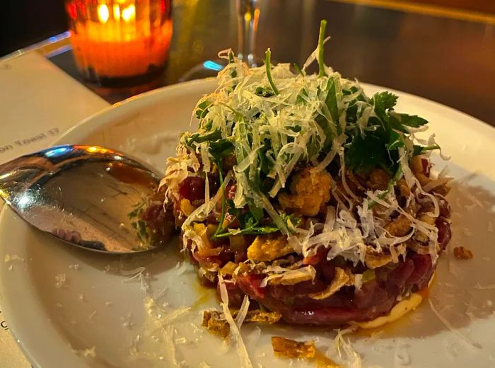 A plate adorned with plenty of greens and cheese, accompanied by a glass of white wine.