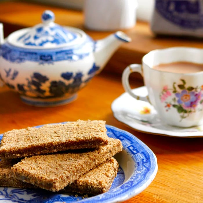 A delicious serving of gingerbread accompanied by a cup and teapot.