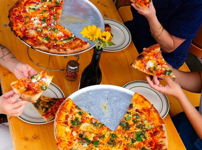 Diners savor two pizzas adorned with various toppings.