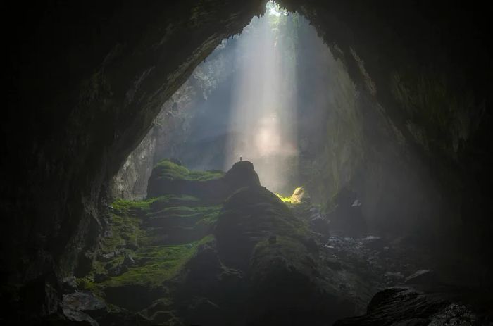 A doline casts a radiant beam of light inside Hang Son Doong cave.