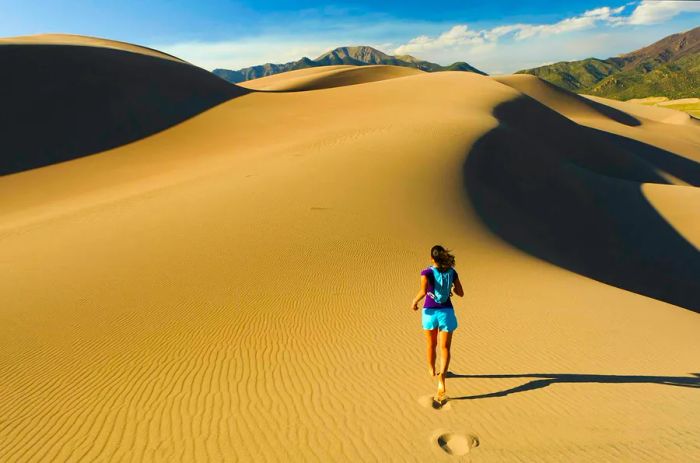 A woman running on a sand dune in Great Sand Dunes National Park, Colorado