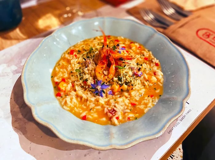 Shrimp elegantly resting on a bowl of savory rice stew.