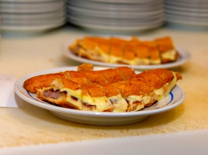 A selection of cachorrinhos (hot dogs served in chopped bread with cheese) lined up on a kitchen counter.