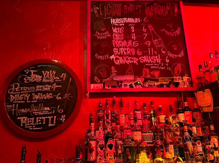 A display of bottles on the back bar under chalkboard menus.