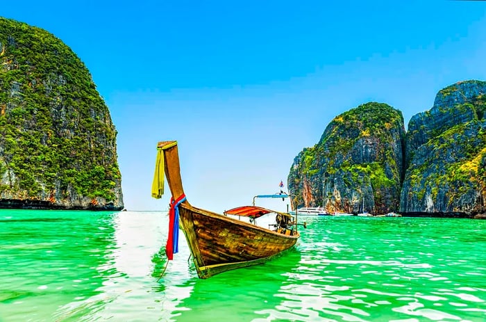 A Thai boat glides through the azure waters of Ao Maya Beach.