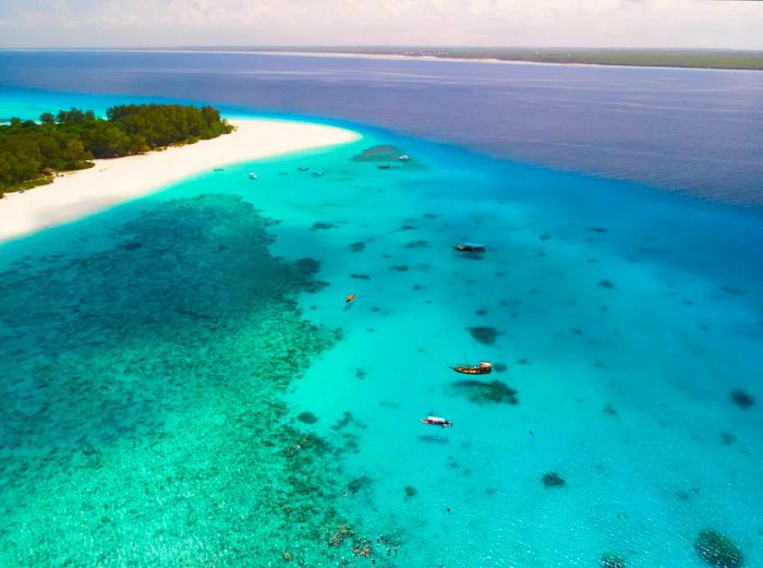 A pristine white sand beach on Mnemba Island, Zanzibar, with a vibrant blue sea.