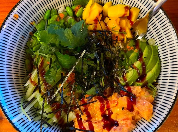 A close-up view of a bowl filled with fish and vegetables, elegantly arranged in sections within a decorative bowl.