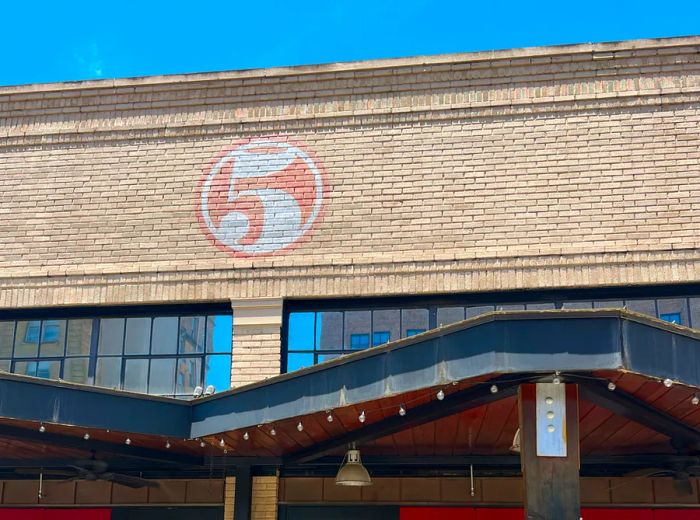 The exterior of the restaurant features a large beige brick building, prominently displaying the number five on its facade.