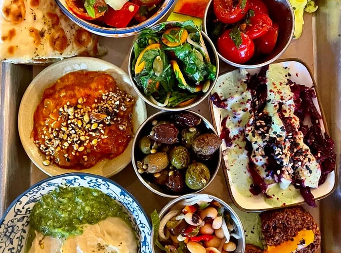 A tray filled with an assortment of vibrant dips, breads, and fresh vegetables.