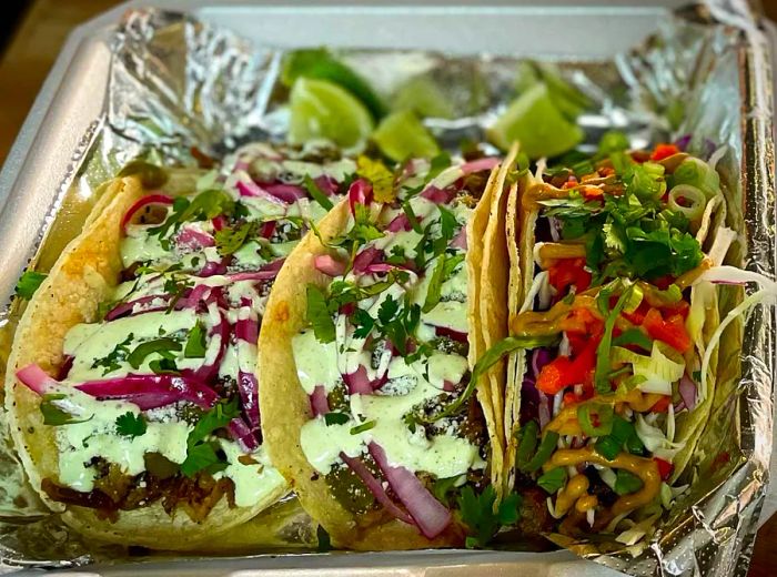 Three tacos served on a tin foil tray.