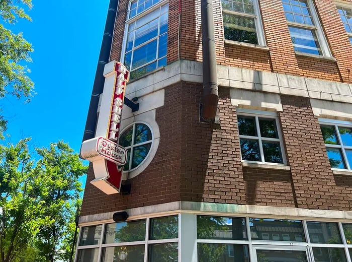 The exterior of the restaurant features redbrick with a prominent illuminated sign that reads Half Shell Oyster House, directing customers towards the entrance.