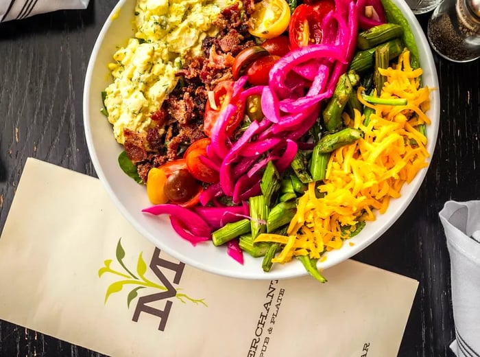 A vibrant cobb salad arranged in distinct rows of colorful ingredients.