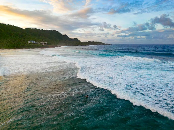 An aerial view captures a surfer riding the waves at Pacifico Beach, Siargao, Philippines.