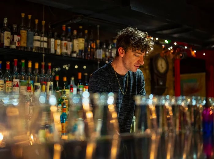 A bartender stands behind a row of gleaming glasses.