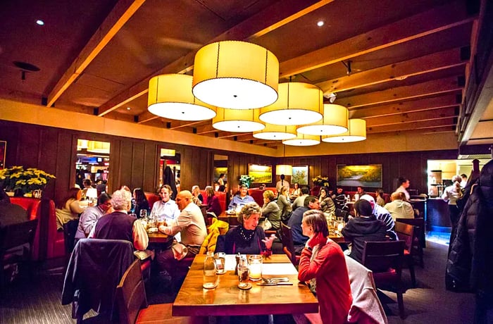 Diners seated beneath a display of midcentury pendant lights.