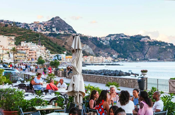 Diners enjoy a sidewalk restaurant on the waterfront in Giardini-Naxos on a summer evening.