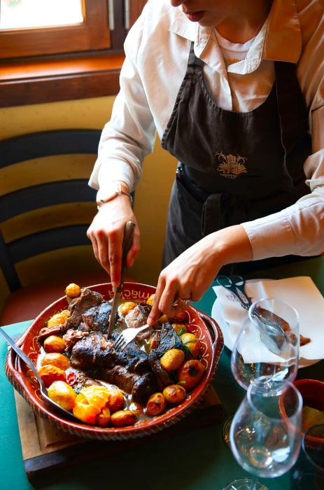 A server slices a generous portion of roast beef onto a platter.