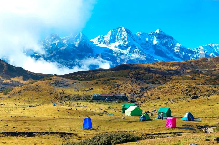 A campsite featuring tents perched atop snow-covered mountains in Sikkim, India.