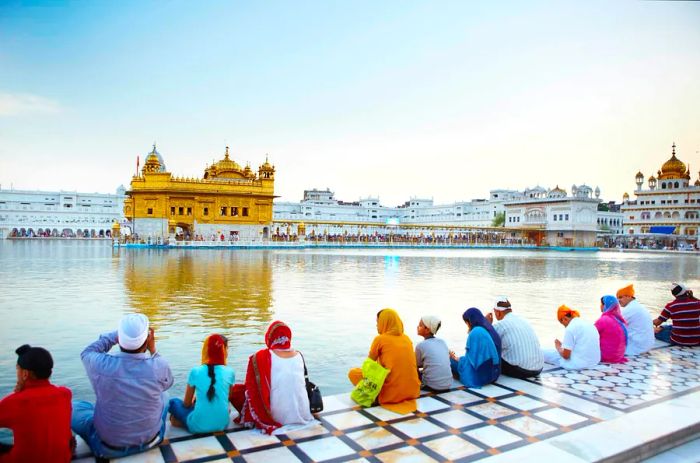 Devotees lining the walkway across the water from the Golden Temple, an impressive structure with a golden facade.