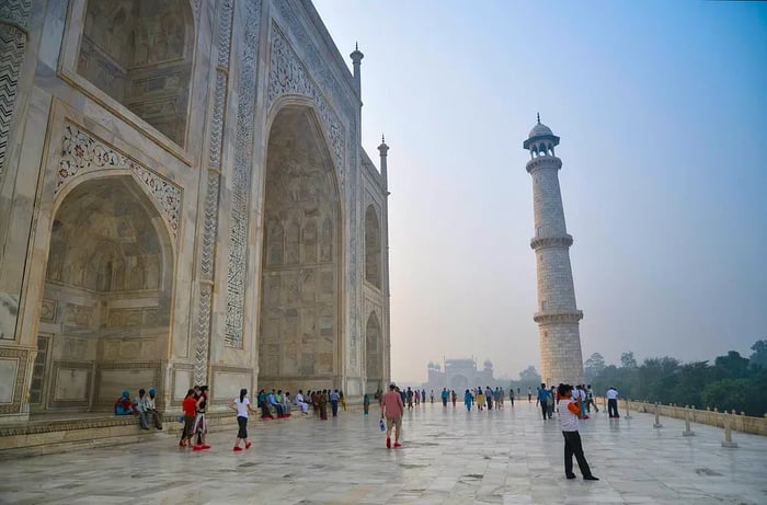 Visitors enjoy the view from the terrace of the Taj Mahal in Agra, India, shrouded in misty light.