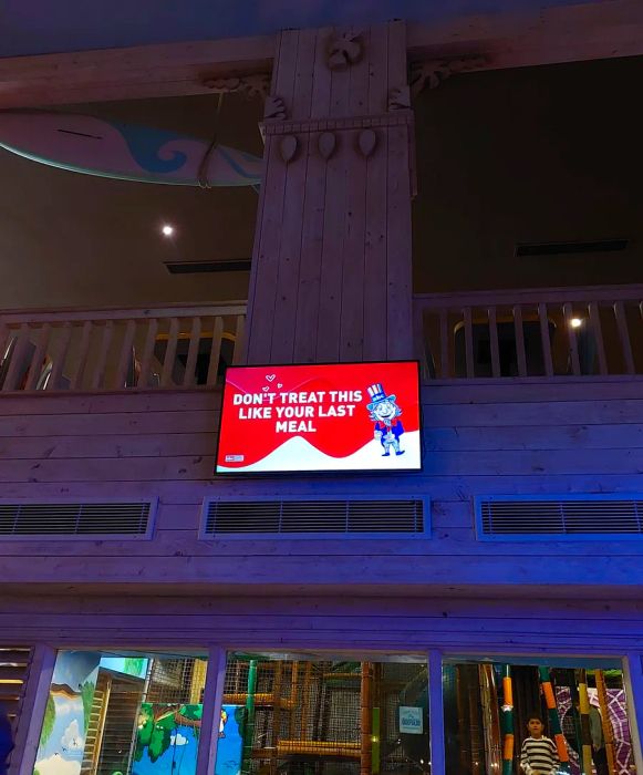 A TV hangs over the dining area displaying a cartoon Uncle Sam with the message: Don’t treat this like your last meal.