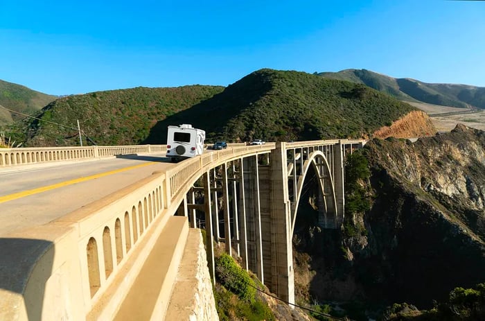 A camper travels across the iconic arched Bixby Bridge in Big Sur