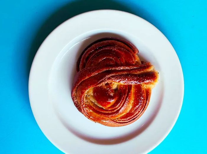 A beautiful overhead view of a braided pastry resting on a plate, contrasted against a vibrant blue background.