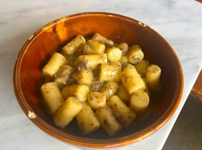 A bowl of gnocchi in a luxurious yellow sauce, beautifully arranged.