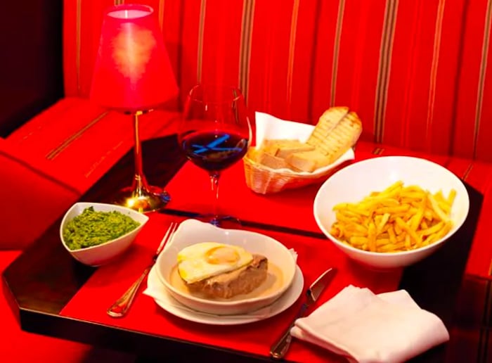 An assortment of dishes laid out on a small table next to a vibrant red patterned booth.