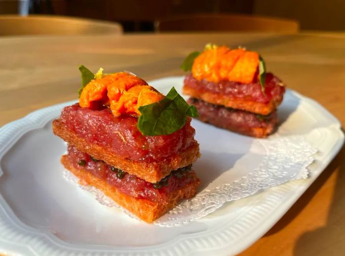 Petite sandwiches stacked with tuna, sea urchin, caviar, and fresh herbs.