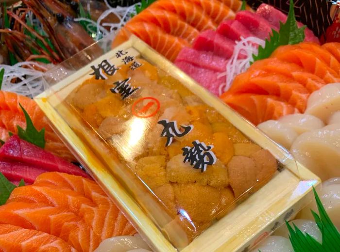 A takeout platter showcases slices of sashimi elegantly arranged around a box of uni.