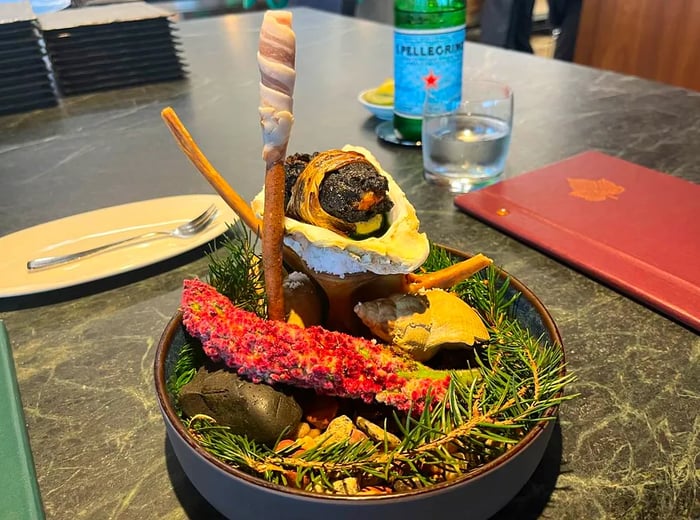 A stunning presentation of oysters arranged on a bed of branches, accompanied by various artistic garnishes.