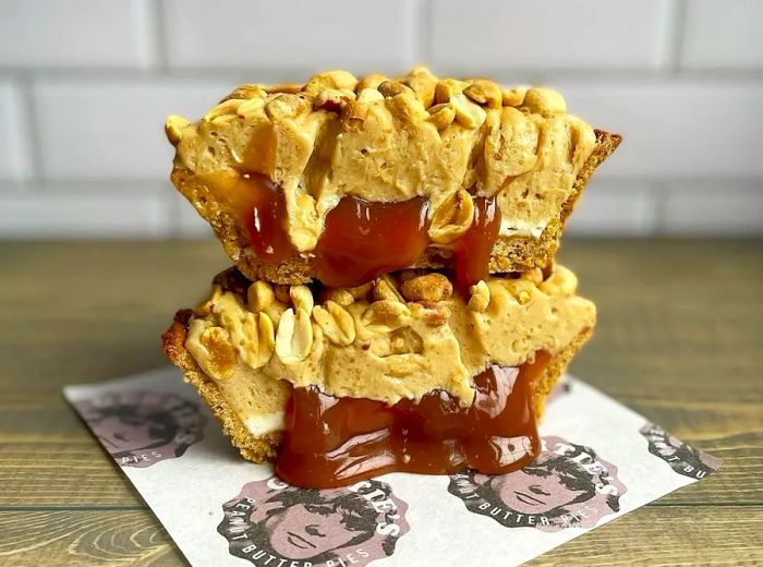 A handheld pie, cut in half to reveal its strawberry jam filling, drips onto a branded Gertie’s napkin.