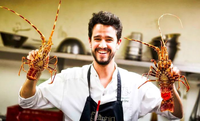 A chef proudly displays two crustaceans.