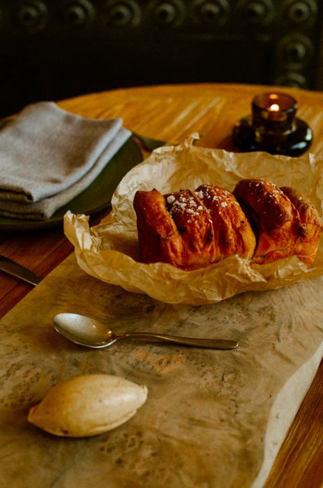 A fluffy loaf of bread wrapped in wax paper, presented on a marble board with a dollop of butter.