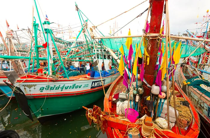 Vibrant boats, filled with fishing equipment, packed tightly into a port.