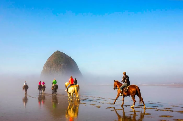 A group of horseback riders by Haystack Rock on Cannon Beach, Oregon, USA