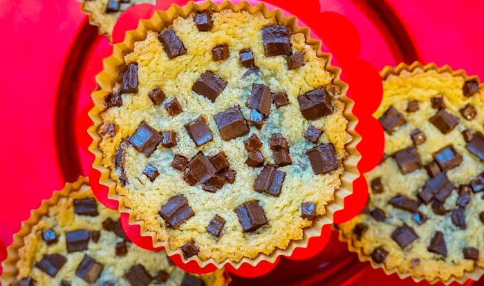 Three oversized chocolate chunk cookies served in plastic cups on a platter.