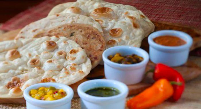 Naan served alongside small bowls of various sauces.