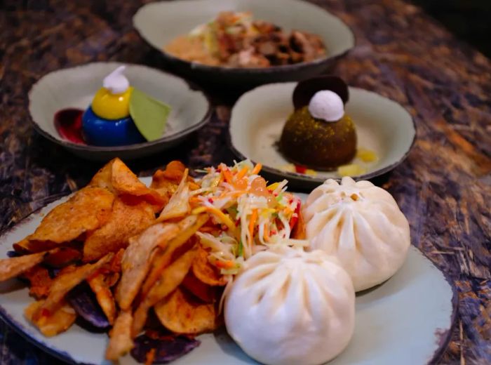 A plate featuring dumplings, chips, and slaw alongside imaginative food creations.