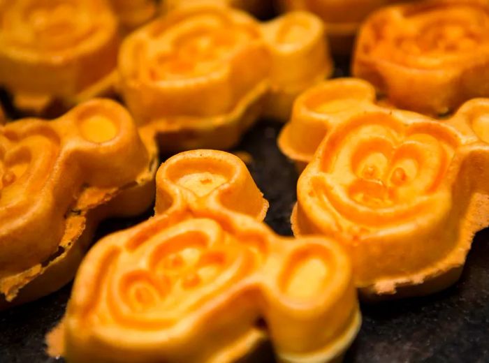 A collection of Mickey Mouse-shaped waffles sizzling on the griddle.