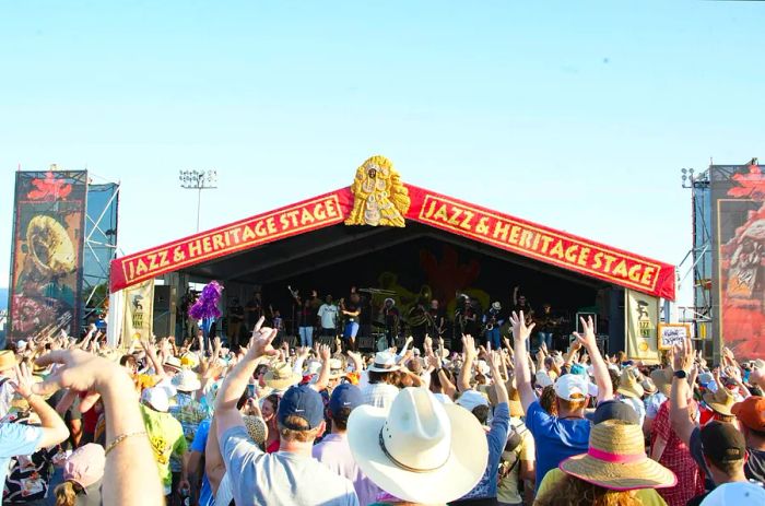 A crowd cheers as a band performs on stage at Jazz Fest in New Orleans