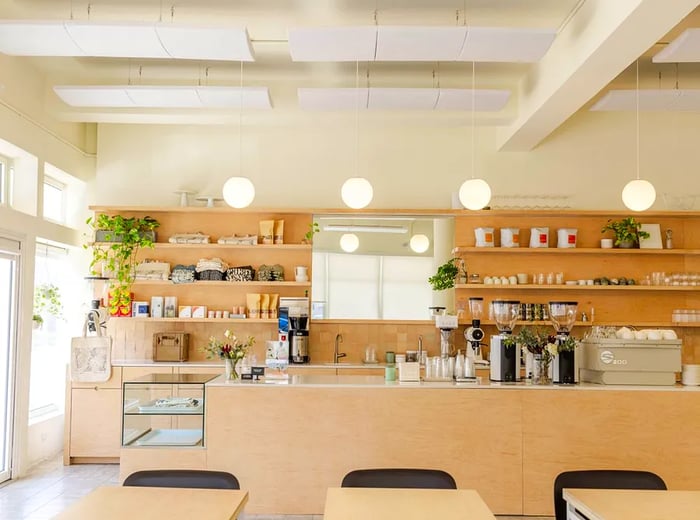 A bright café featuring light blond wood accents and stylish pendant lights.