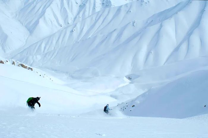 Two skiers navigate through the breathtaking mountainous wilderness of Uzbekistan.