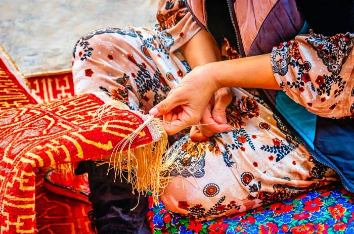 A close-up of a female Uzbek carpet weaver creating a traditional oriental silk carpet in Itchan Kala Old Town.