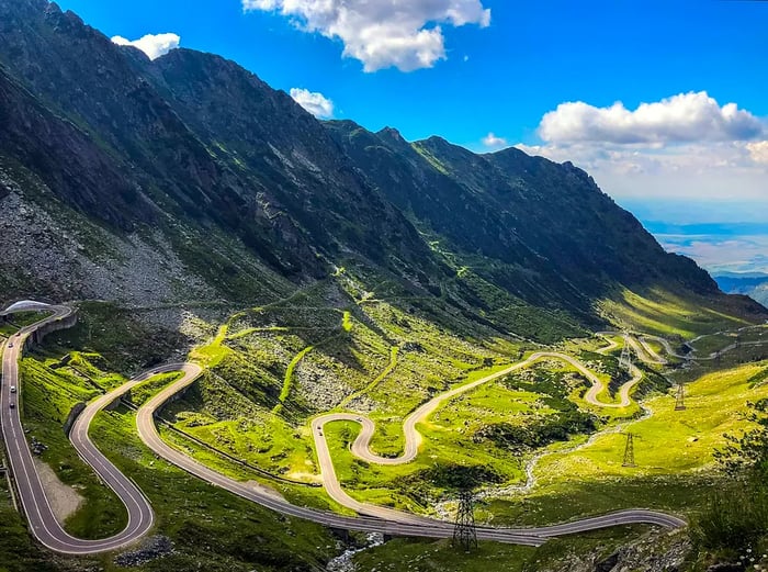 The winding Transfăgărășan mountain road in Romania, basking in sunlight.