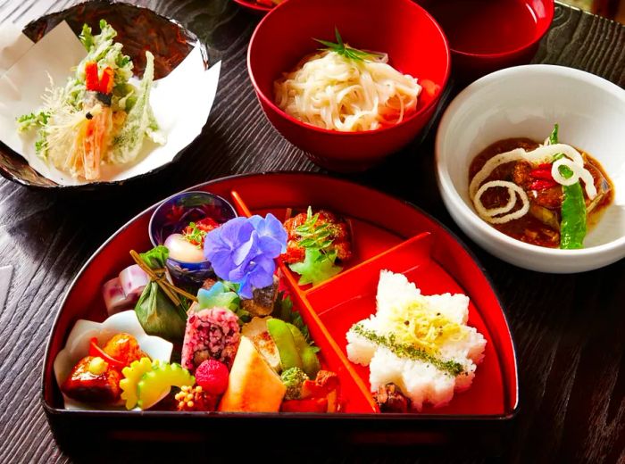 A vibrant assortment of dishes presented in a bento box alongside side bowls.