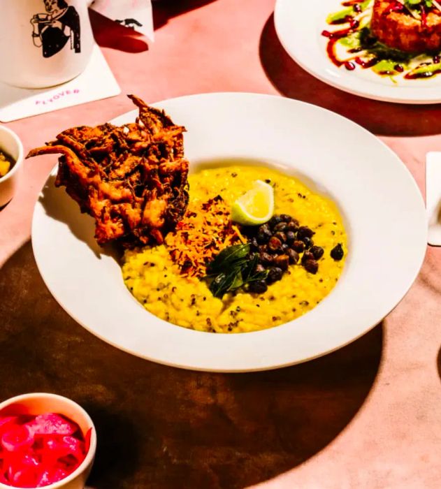 A vibrant yellow bowl of khichri accompanied by a large fritter.