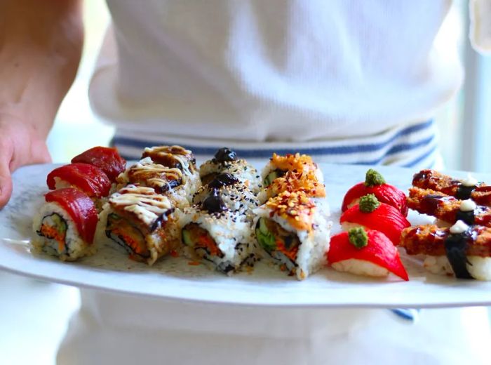 A staff member presents a tray of vegan sushi.