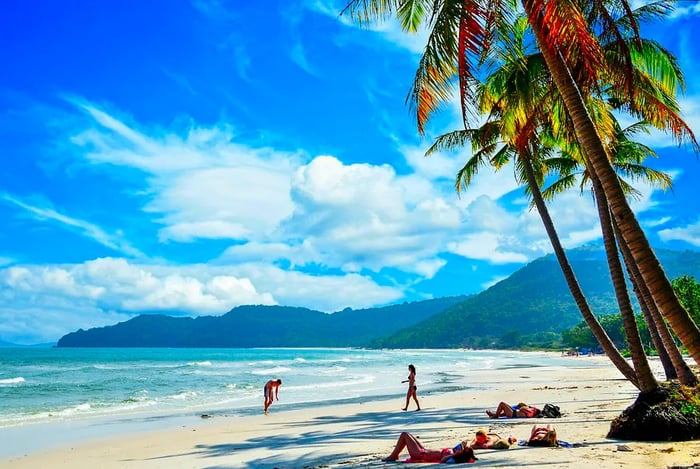 Visitors enjoying the white-sand shores beneath palm trees at Khem Beach, Phu Quoc Island, Vietnam